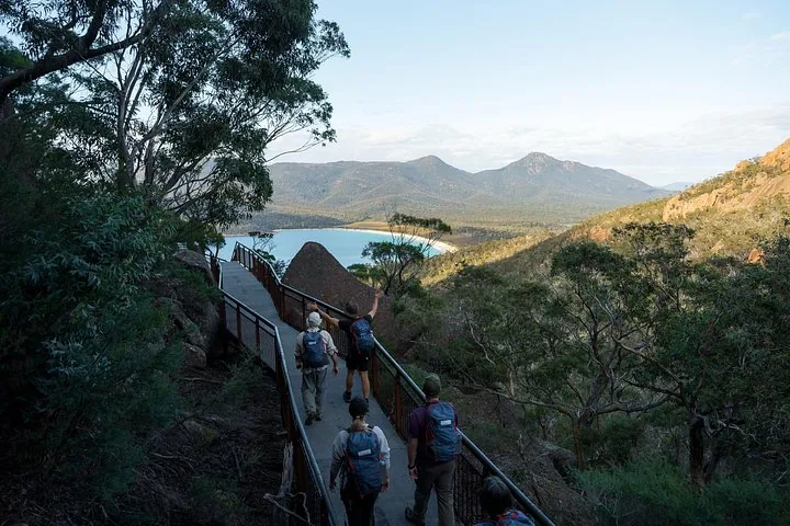 Hikers walking down a wooden boardwalk overlooking Wineglass Bay.